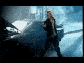 a man is standing in front of a black car with the hood up .