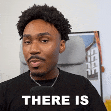 a man sitting in a chair with a microphone and the words " there is " behind him