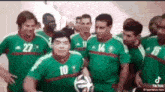 a group of men in green jerseys are standing next to each other and holding a soccer ball .
