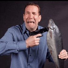 a man in a striped shirt is holding a fish and a gun