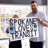 a man and a child hold up a sign that says spokane loves transit