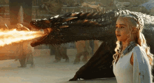 a woman in a white dress stands in front of a dragon with fire coming out its mouth