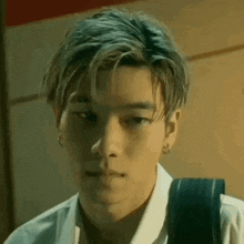 a close up of a young man wearing a white shirt and a black backpack .