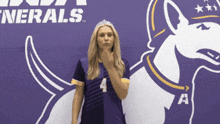 a woman wearing a tiara and number 4 jersey stands in front of a purple background with the word nerals on it