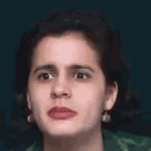 a woman in a green shirt is making a funny face with her mouth open .