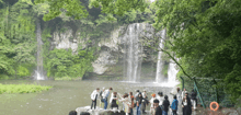 a group of people standing near a waterfall in the woods