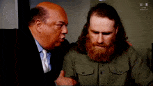 a man with a beard is talking to another man in front of a sign that says win live kansas city