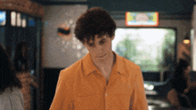 a man in an orange shirt is standing in front of a sign that says ice cream