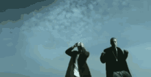 two men are dancing on a rooftop in front of a city skyline