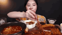 a woman is eating food with chopsticks from a bowl