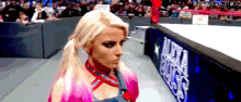 a woman is standing in a wrestling ring with a crowd watching .
