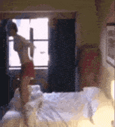 a woman is jumping on a bed in a bedroom