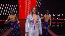 a man in a silver and purple wrestling outfit is walking down a ramp