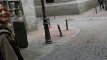 a person walking down a cobblestone street with graffiti on the side of the building