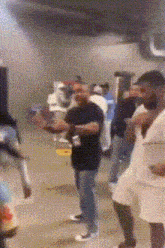 a group of people are standing in a room and one of them is holding a bottle of beer