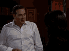 a man in a white shirt and a woman in a black jacket are talking to each other