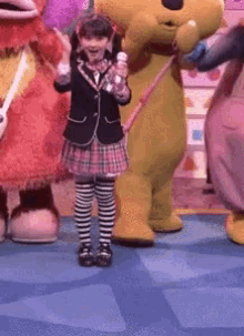 a girl in a plaid skirt is holding a microphone in front of a group of stuffed animals