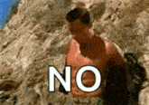 a shirtless man is standing in the dirt with the word no written on the ground .