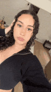 a woman with curly hair is taking a selfie with her hand in her hair