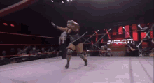 a woman is wrestling in a wrestling ring while a referee watches .