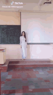 a woman in a white dress is standing in front of a blackboard with tiktok written on the bottom right