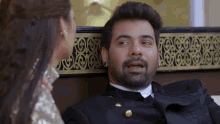 a man with a beard is talking to a woman in a gold dress