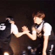 two men are standing next to each other and shaking hands . one has the number 5 on his shirt .