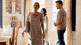 a woman in a striped dress is walking through a room with a man and a woman .