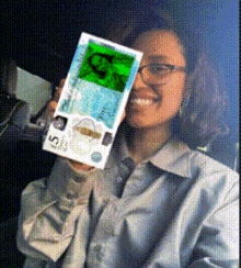 a woman is holding a 5 dollar bill in front of her eye