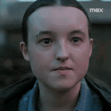 a close up of a woman 's face with a max logo in the background .