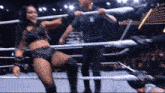 a woman in a wrestling ring with a man holding a bat behind her