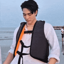 a man wearing a life vest stands on the beach