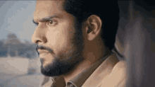 a man with a beard is looking out the window .