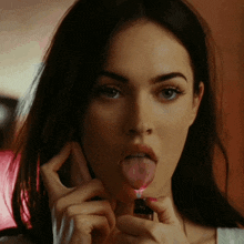 a woman is sticking her tongue out while holding a lighter to her mouth