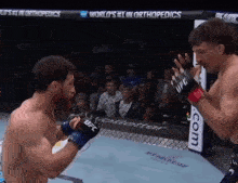 two men are fighting in a boxing ring with a sign that says world 's # 1 in orthopedics behind them