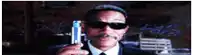a man wearing sunglasses and a hat is holding a can of beer .