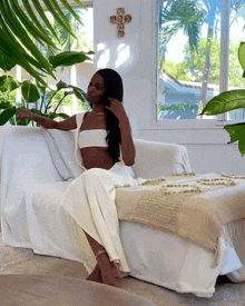 a woman is sitting on a white couch with a cross on the wall behind her
