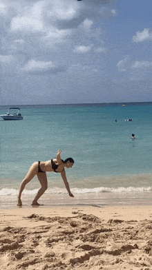 a woman in a bikini is standing on one leg on the beach