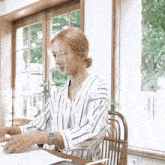a woman wearing a watch sits at a table with papers