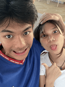 a boy and a girl are posing for a picture and the boy is wearing a blue shirt with the word yhhot on the sleeve
