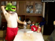 a man wearing a frog mask is dancing in a kitchen