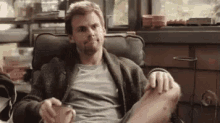 a man is sitting in a chair with his feet up and a cup of coffee .