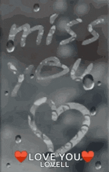 a heart is drawn on a window with the words `` miss you '' and `` love you '' written on it .