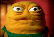 a close up of a cartoon character with big eyes and a green shirt