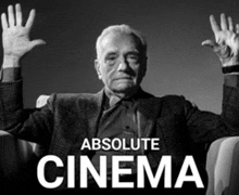 a man in a suit sits in a chair with his hands in the air and the words absolute cinema above him