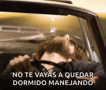 a man is sleeping in a car with the words no te vayas a quedar dormido manejando above him .