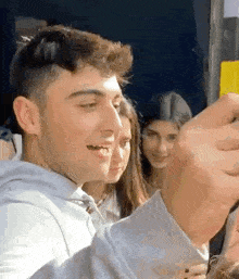 a young man is taking a selfie with a cell phone while standing next to a woman .