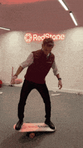 a man is balancing on a skateboard in front of a sign that says redstone