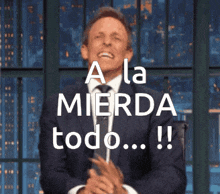 a man in a suit and tie is clapping with the words a la mierda todo written above him
