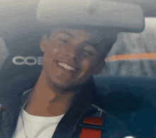 a man is smiling in a car with the word coe on the seat